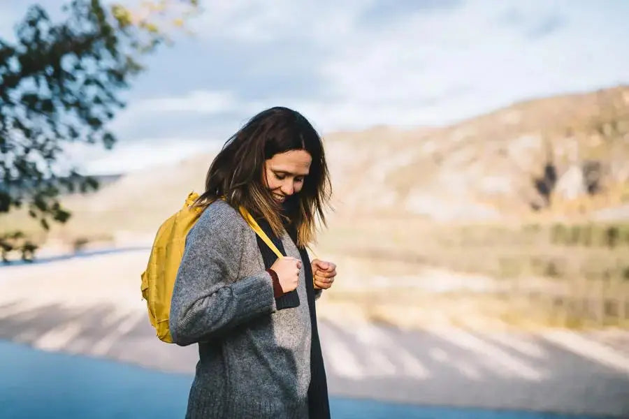 En dame med mørkt hår står ute i skogen, med en gul sekk på ryggen. Vitamin C Immune System
