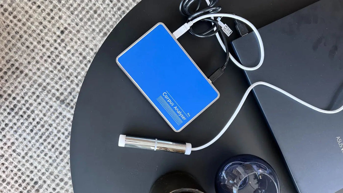 En blå vitaminmåler med ledninger ligger oppå et sort, lite bord