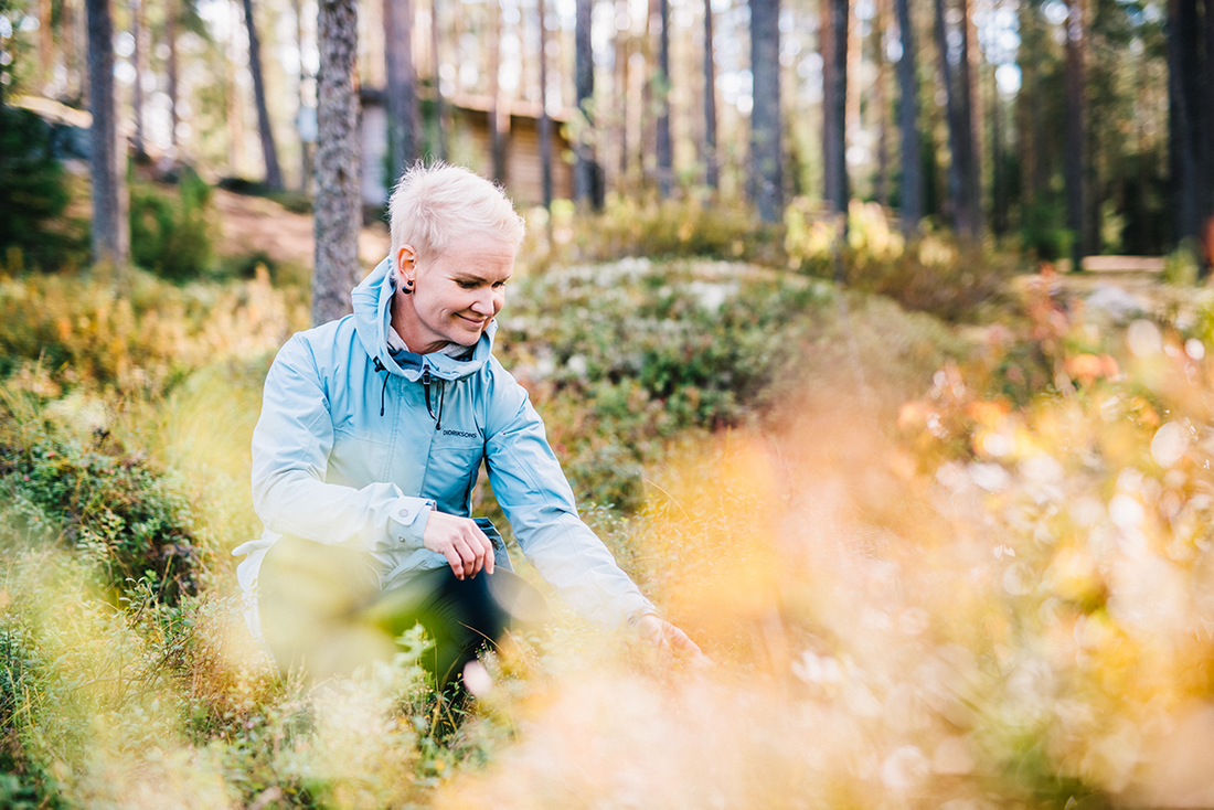 En dame med hvitt hår og blå jakke står ute i skogen og sanker. Zinc Benefits for Health