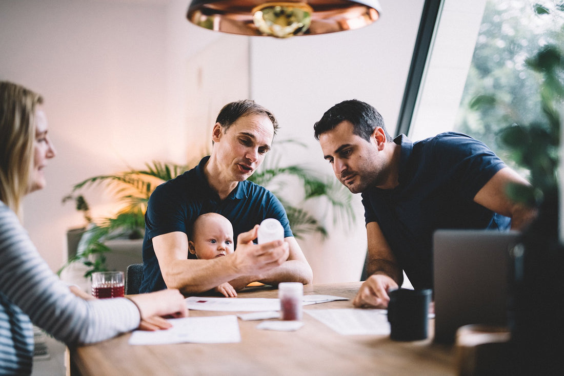 På bildet sitter det to menn, en dame og en baby i fanget til den ene mannen. De ser alle tre på en pc-skjerm og diskuterer kosttilskudd og Aarja Health