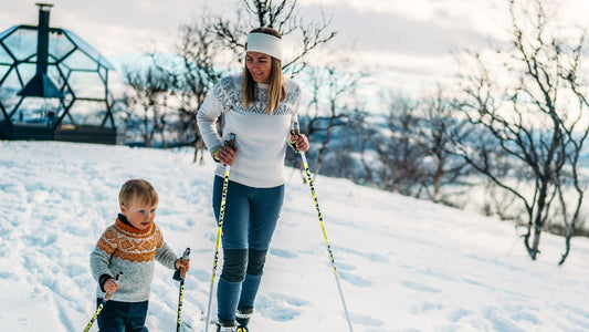 Det er lys dag og en dame og et barn står på ski. De har på seg ullgensere og smiler. Artikkelen handler om hvordan en best kan takle mørketida.