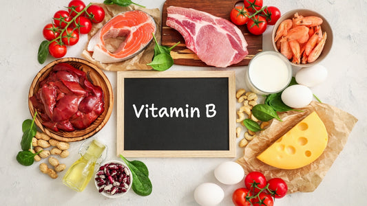 På sort skoletavle står det skrevet med kritt "Vitamin B" rundt den ligger det flere ulike matgrupper som kjøtt, ost, grønnsaker, tomater, linser og egg